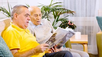 Zwei Senioren lesen in einer AllgäuPflege-Einrichtung ein Buch