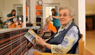 Eine Seniorin liest ein Magazin im Spital Sonthofen