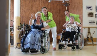 Mitarbeiterinnen schieben Bewohnerinnen im Rollstuhl durchs Spital Sonthofen