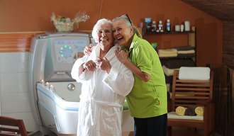 Zwei ältere Frauen lachen und umarmen sich