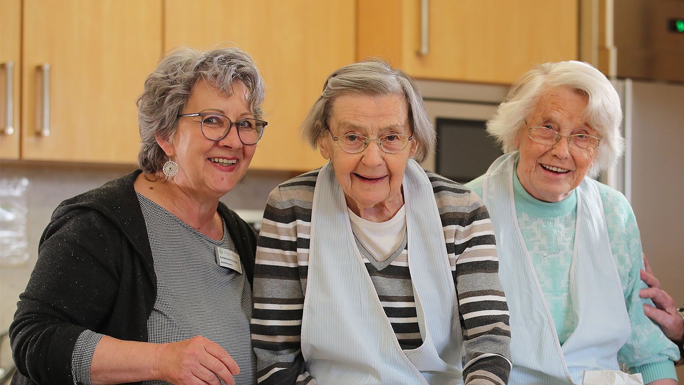 Vier Seniorinnen hocken nebeneinander