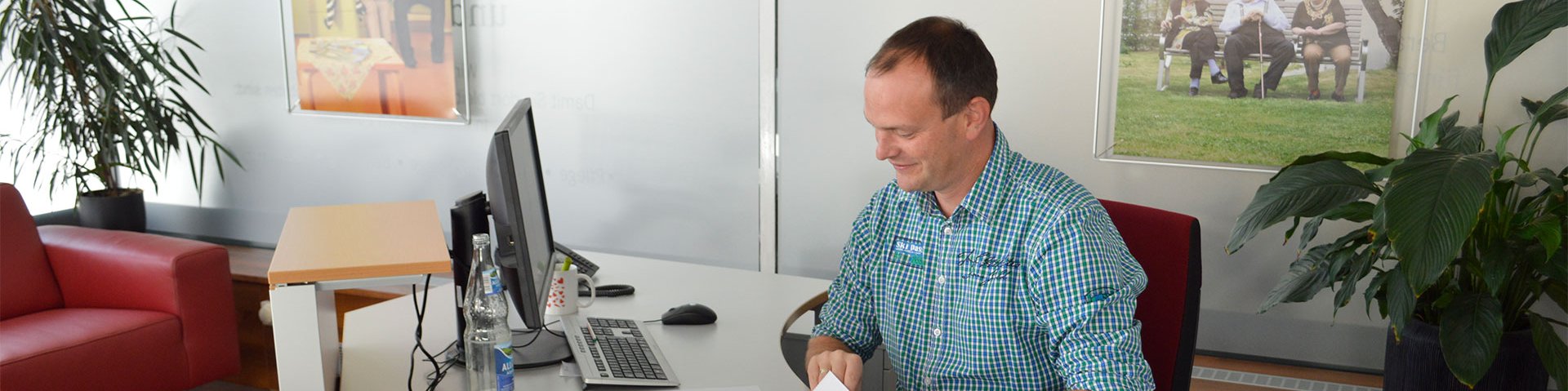 Ein Mann am Schreibtisch mit Papieren und einem Bildschirm vor sich